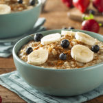 Blue bowl full of oatmeal, bananas, and blueberries