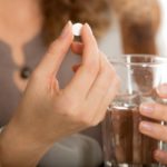 woman-taking-tablet-with-water