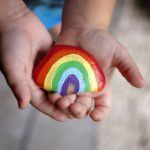 Young Child's LIttle Hands Holding Painted Rainbow Rock