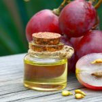 grape-seed-oil-in-a-glass-jar-and-fresh-grapes-on-old-wooden-table-in-picture-id1060744718