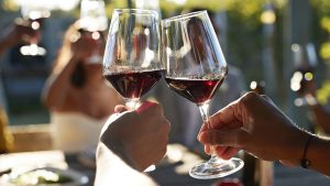 Friends toasting glasses with red wine in wedding